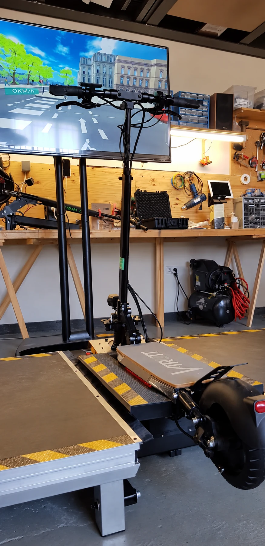 Trottinette VTrott sur sa plateforme, devant un écran sur pied, dans un atelier