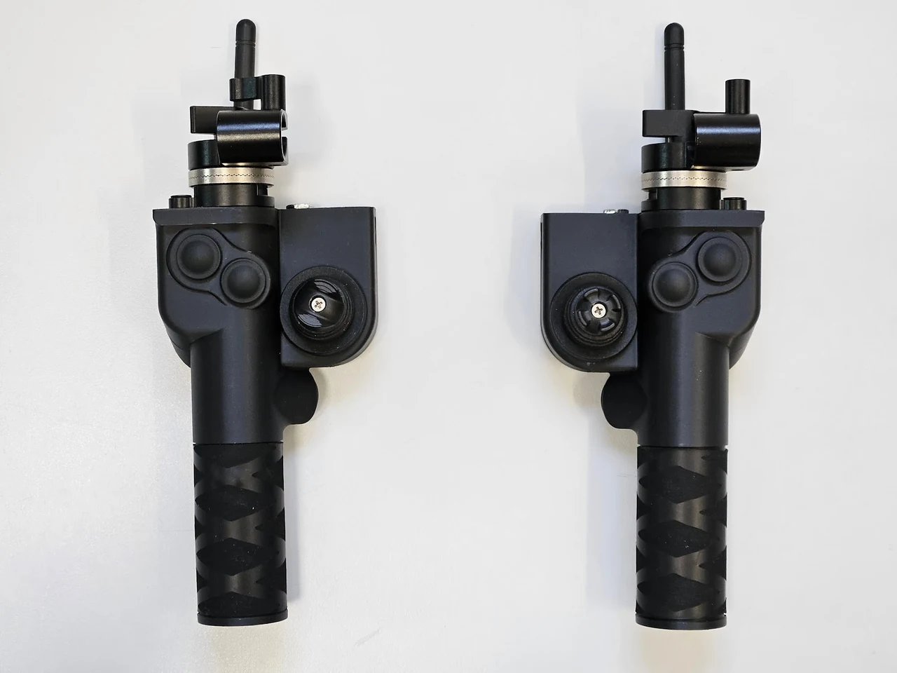 Deux poignées noires de la VCam côte à côte, sur fond blanc