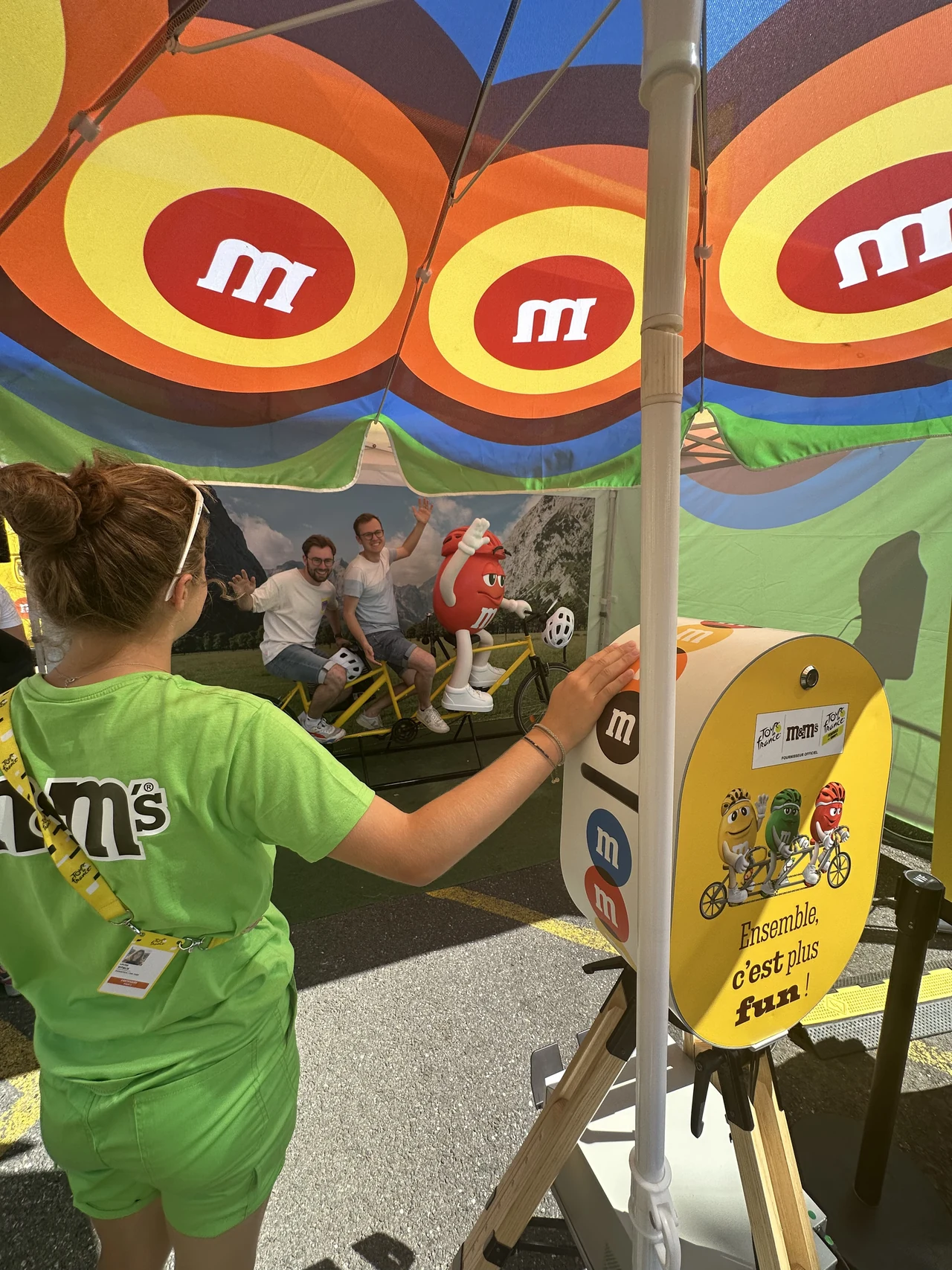 Enfant utilisant une borne photo jaune sur trépied devant un décor de marque coloré