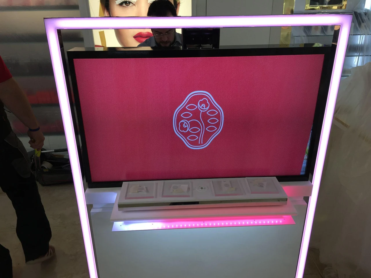 Gros plan sur l’écran rose au logo Shiseido, encadré d’un liseré lumineux, au-dessus d’un plateau à produits