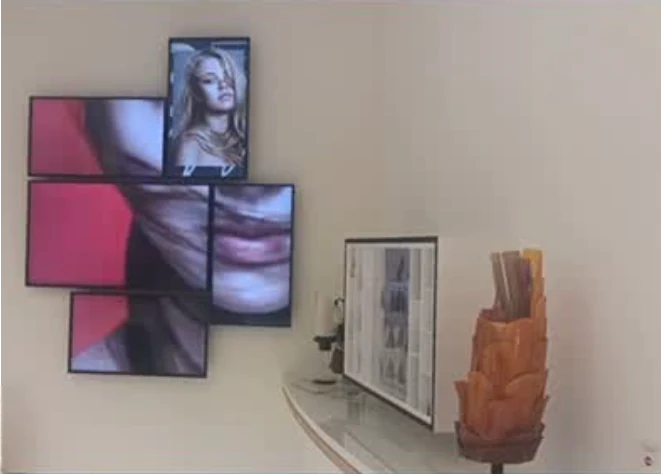Mosaïque d’écrans affichant des visages, écran sur un comptoir blanc et sculpture orange du corner Henkel / Schwarzkopf
