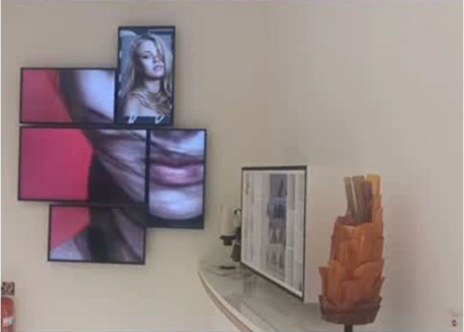 Mosaïque d’écrans de visages au mur, écran sur le comptoir et sculpture orange au bout du comptoir