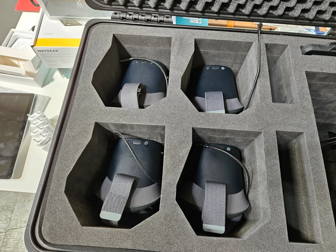 Gros plan sur les compartiments en mousse d’une mallette, avec quatre casques VR noirs rangés