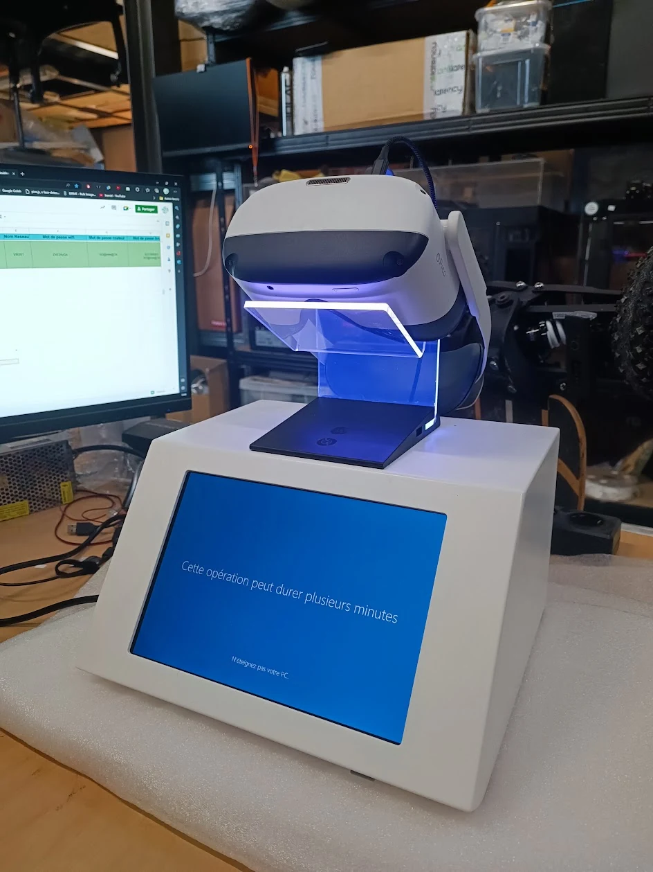 Showcase blanc compact avec écran bleu et casque VR posé dessus, dans un atelier