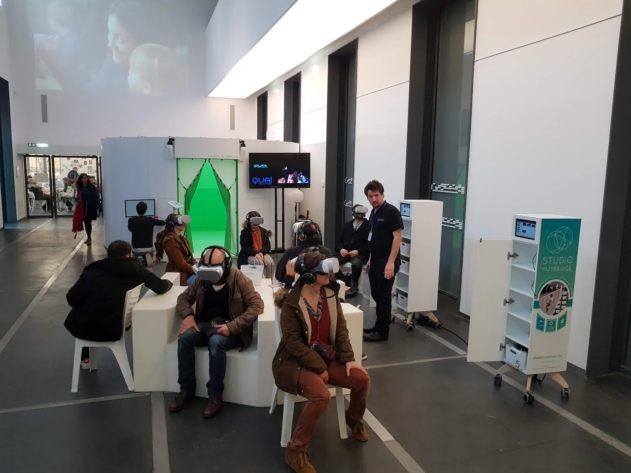 Personnes casque VR sur la tête, assises dans un espace d’exposition, avec des meubles Jukebox VR à proximité