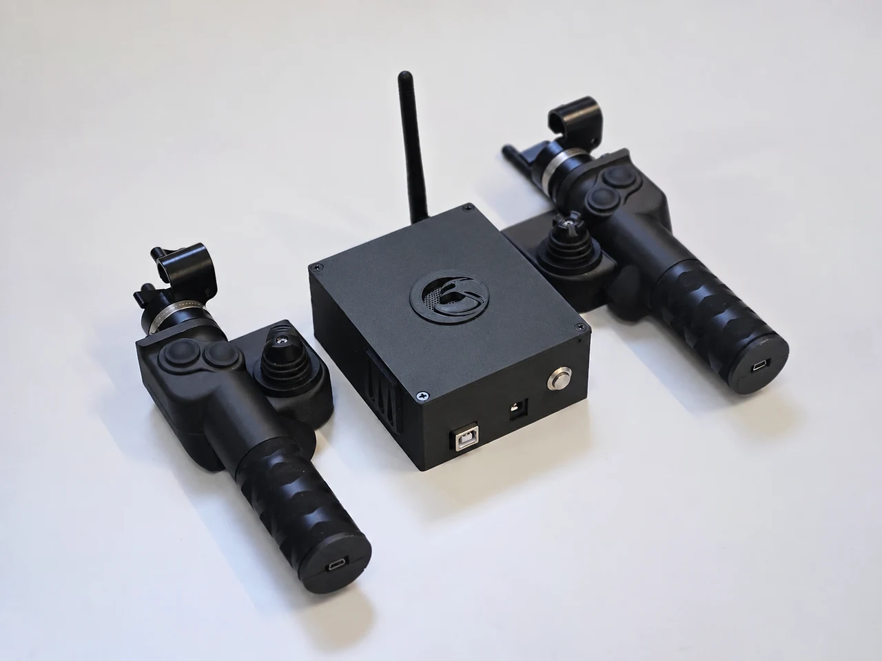 Deux poignées et un boîtier récepteur noir à antenne, sur fond blanc