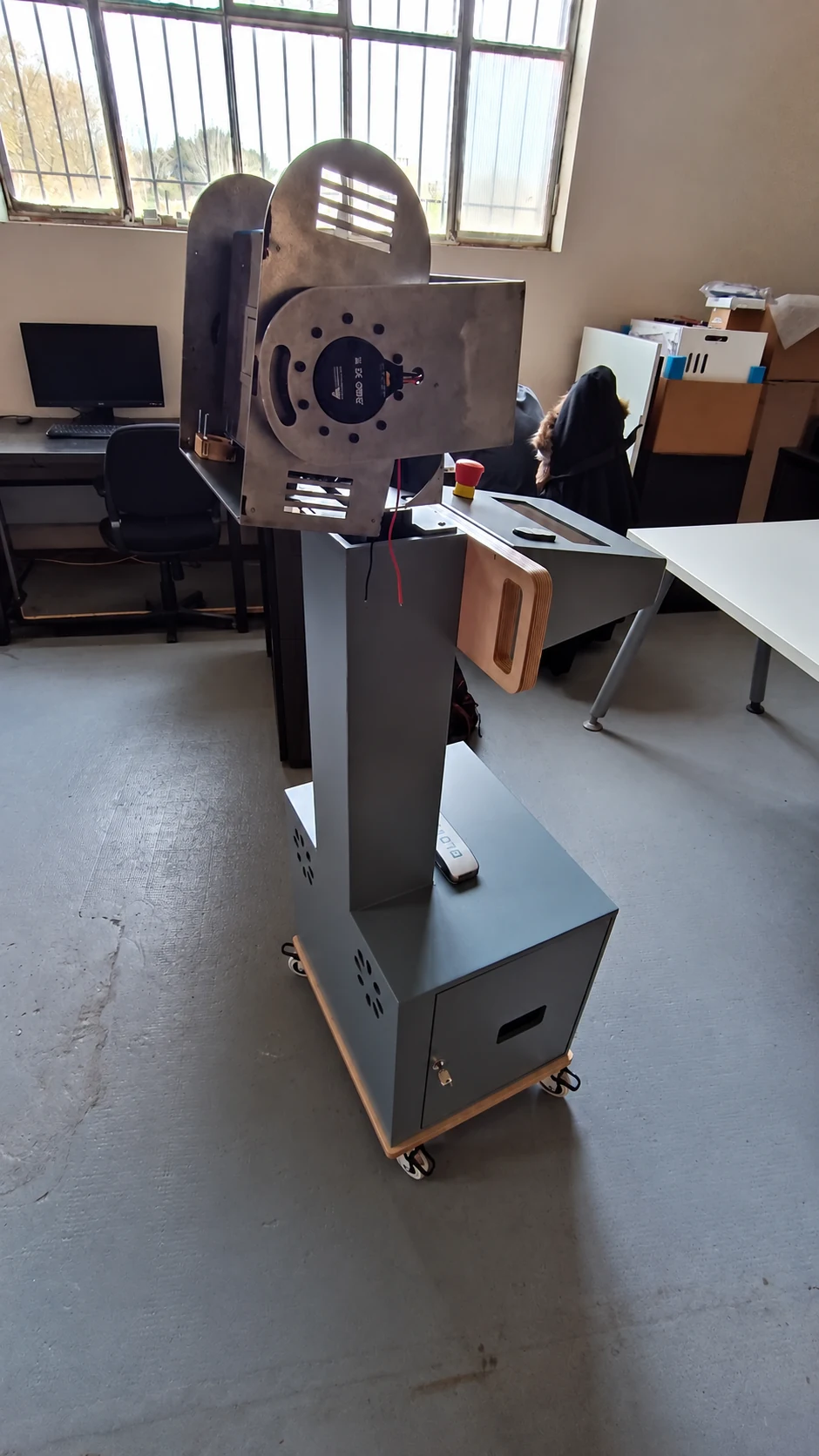 Unité Wally grise sur roulettes : colonne portant une tête de projection orientable, dans un atelier